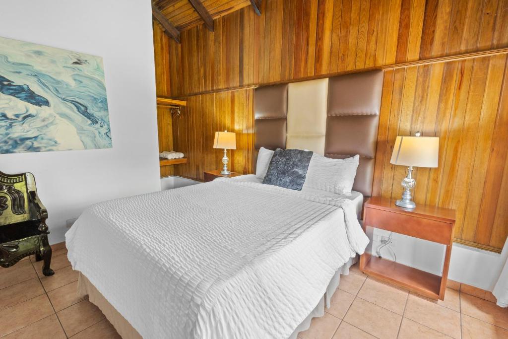 sypialnia z białym łóżkiem z drewnianymi panelami w obiekcie H4 LAS CABAÑAS w mieście Corozal