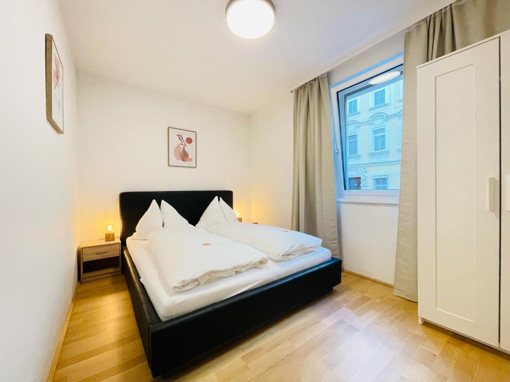 Schlafzimmer mit einem Bett mit weißer Bettwäsche und einem Fenster in der Unterkunft Vienna Style Apartment in Wien