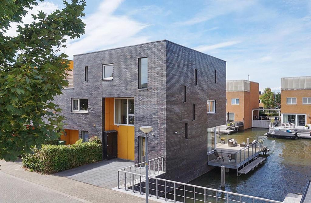 a black brick house on the water with a marina at Chico in Almere