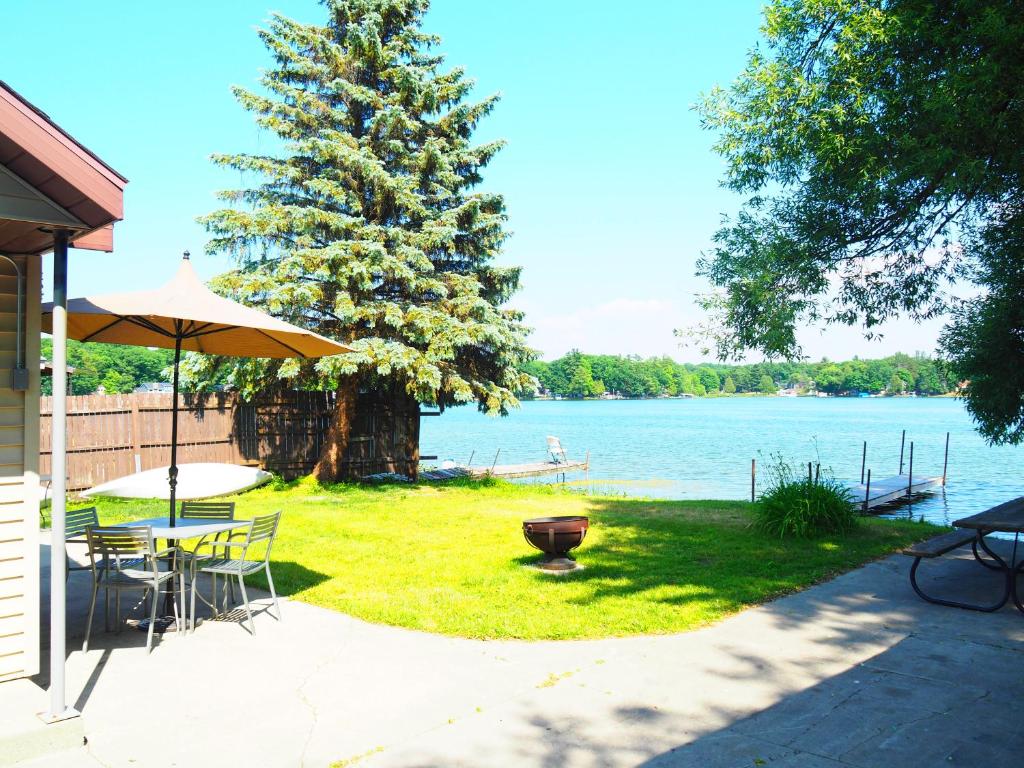 a patio with a table and an umbrella and the water at New! The Turk Lake House - Lakefront With Toys! in Greenville