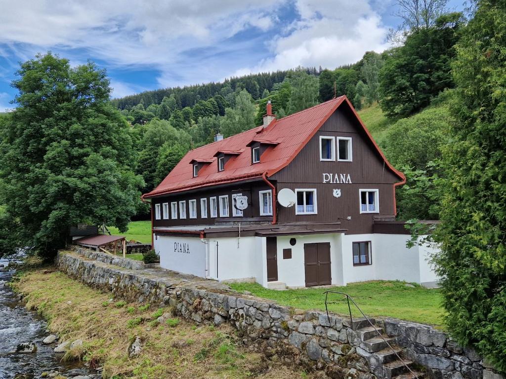 una casa en una colina junto a un río en Pension Piana en Pec pod Sněžkou