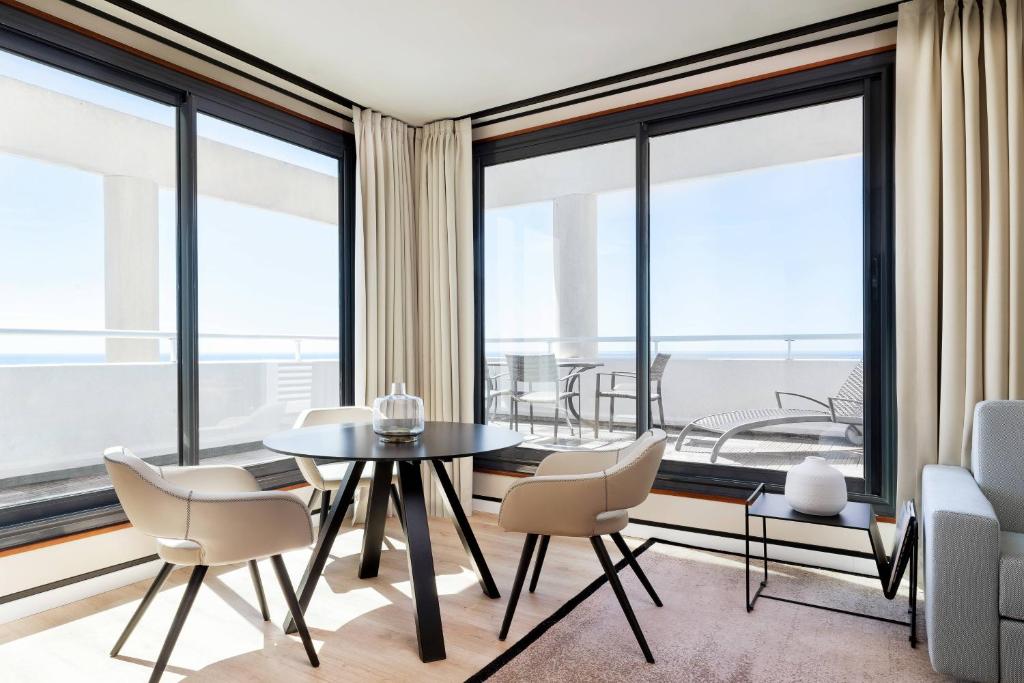 a dining room with a table and chairs and large windows at Riviera Marriott Hotel La Porte De Monaco in Cap d'Ail