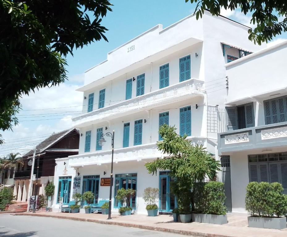 a white building with blue shutters on a street at Villa Merry Lao Ban Aphay in Luang Prabang