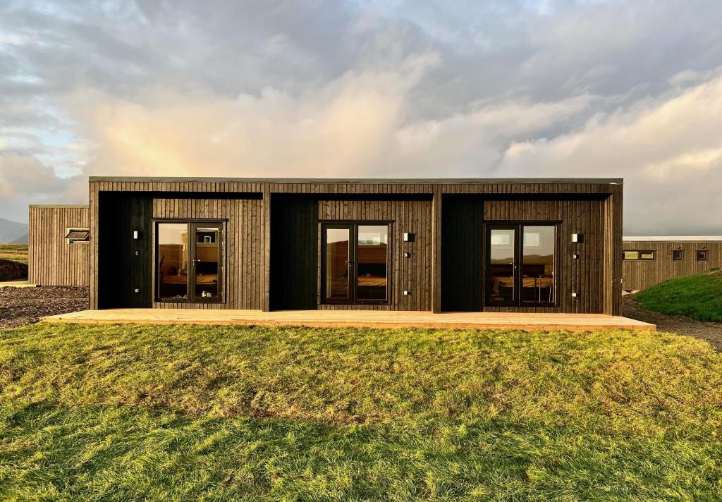 una casa en una colina con césped con un edificio en REY Stays - Small & Cozy Studio, en Höfn