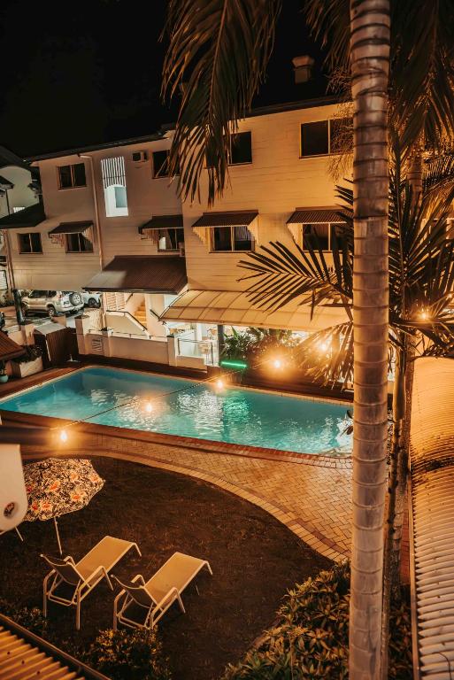 a swimming pool with two chairs next to a building at Cairns Queens Court in Cairns