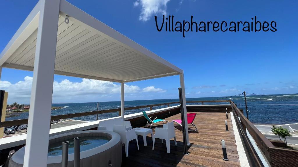 una terraza con mesa, sillas y el océano en VILLA PHARE CARAÏBES Guadeloupe, en Le Moule