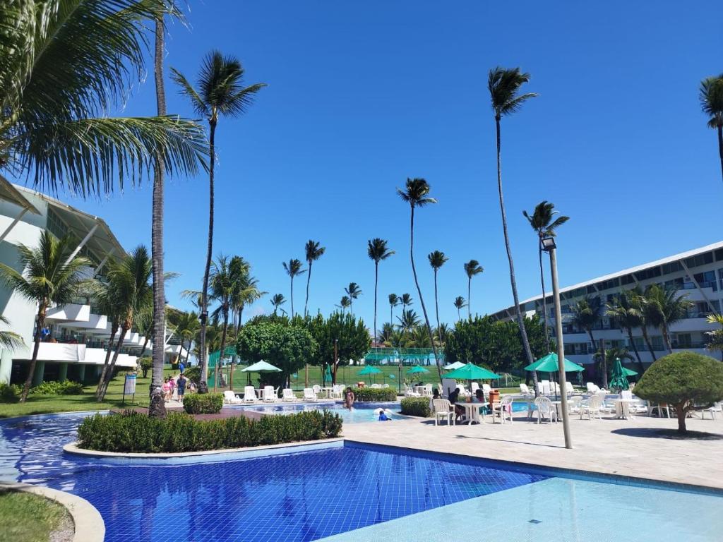 ein Pool in einem Resort mit Palmen in der Unterkunft Ancorar Flat 4203 in Porto De Galinhas