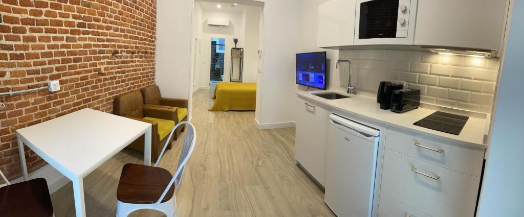 a kitchen with a white counter and a table and a room at Brand NEW Studio Centro, Atocha - Museums in Madrid