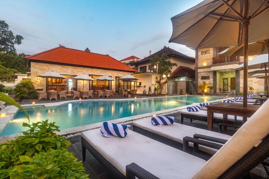 a swimming pool with lounge chairs and an umbrella at Hotel Segara Agung in Sanur