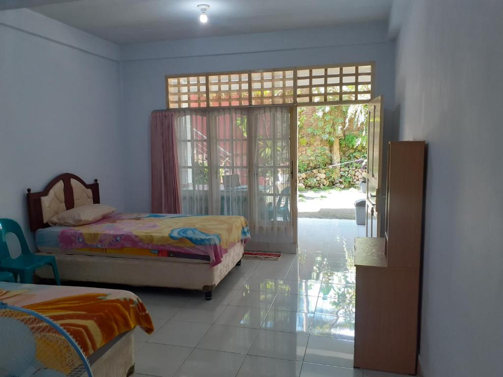 a bedroom with two beds and a sliding glass door at Riana's Homestay in Rantepao