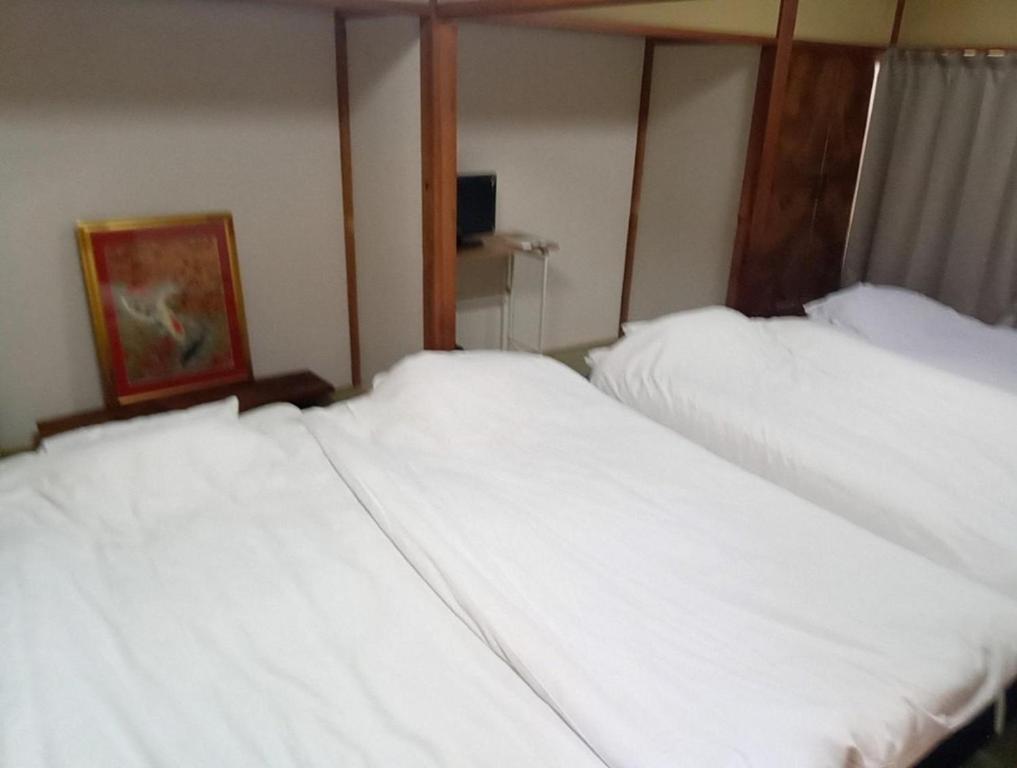 two beds in a room with white sheets at 神亀庵 in Tokyo