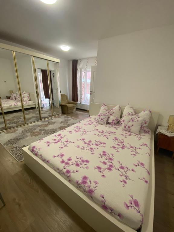 Un dormitorio con una cama con flores púrpuras. en Ardelean Apartment, en Oradea