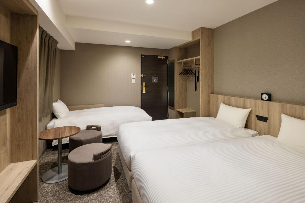 a hotel room with two beds and a table at the b namba-kuromon in Osaka
