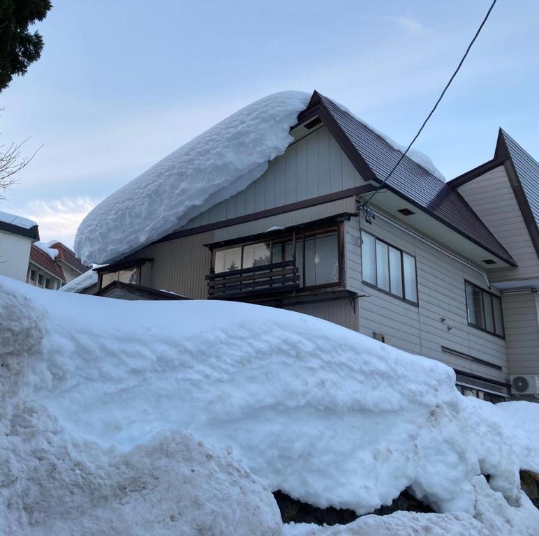 a pile of snow in front of a house at Elan Lodge Akakura in Nagano