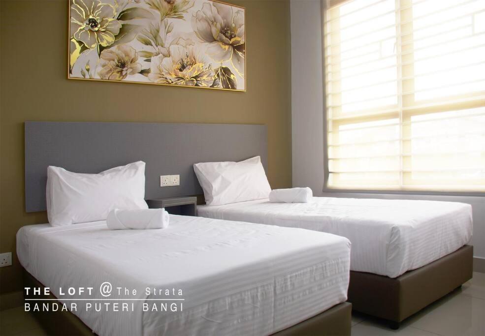 two beds in a bedroom with a painting on the wall at THE LOFTMaple Bandar Puteri Bangi in Kajang