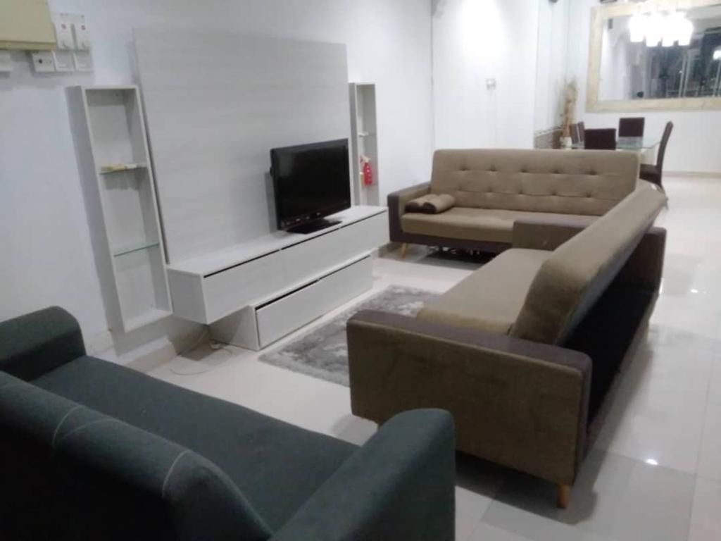uma sala de estar com dois sofás e uma televisão em Homestay Legacy Yumai Kuala Rompin em Kuala Rompin