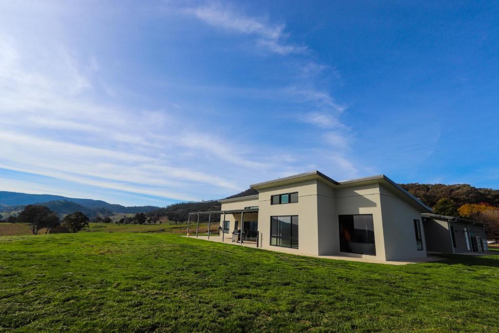 une maison sur une colline avec un champ vert dans l'établissement Widdo's Place, à Tumbarumba