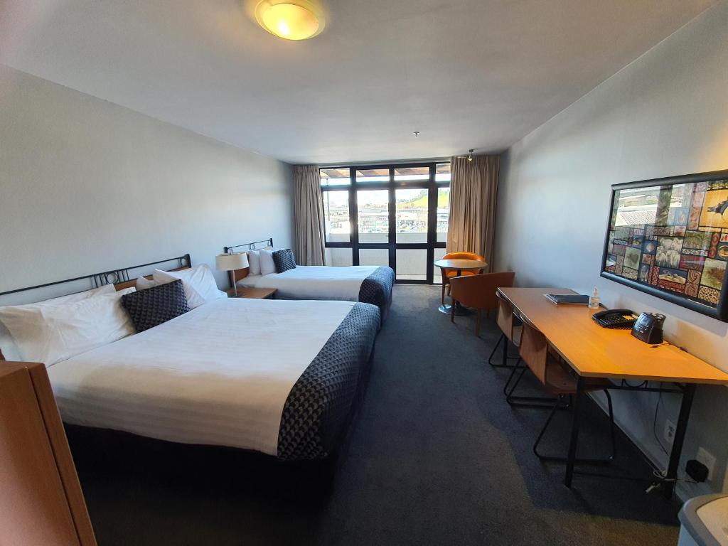 a hotel room with two beds and a desk at Off Broadway Motel in Auckland
