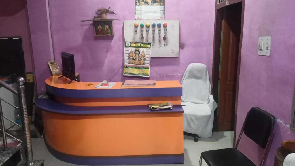 OYO Hotel Krishna Internation في مظفربور: غرفة أرجوانية مع مكتب مع كرسي أبيض