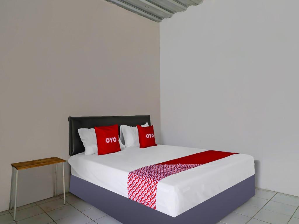 een slaapkamer met een bed met rode kussens bij OYO 90809 Homestay Black Pink Merah Jambu Syariah in Garut