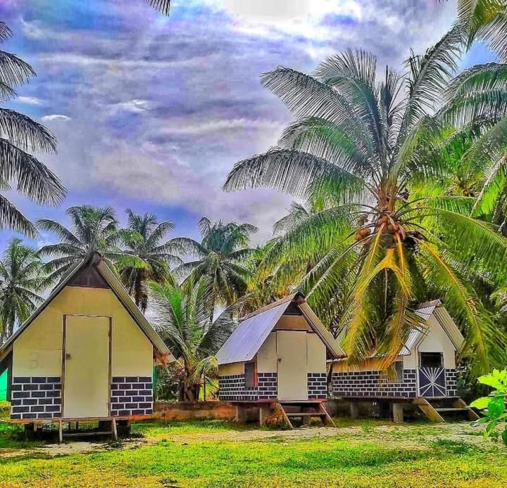 a row of houses with palm trees in the background at Moanarani Camping in Avatoru