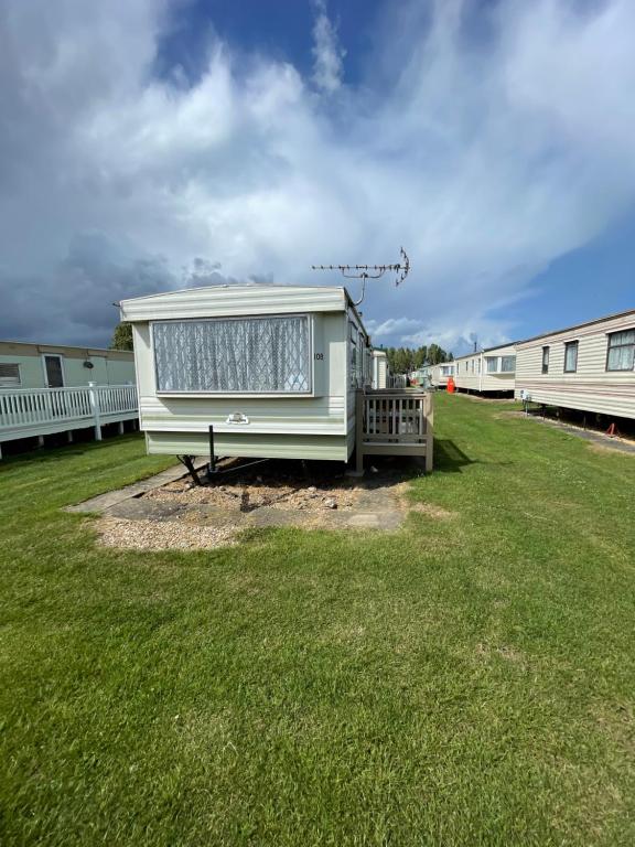 a mobile home sitting in a yard next to a building at Tessas caravan breaks in Chapel Saint Leonards