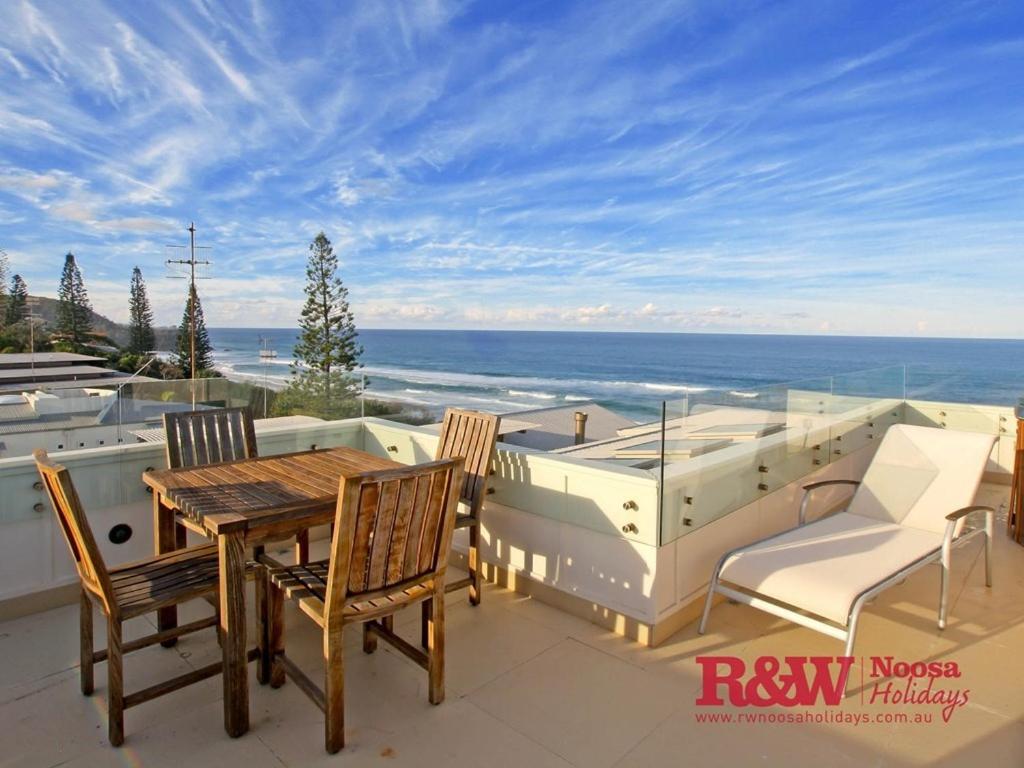 a patio with a table and chairs and a hot tub at The Beachshack, 19 The Esplanade, Sunshine Beach in Noosa Heads