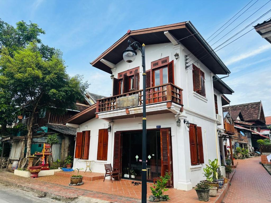 a white house with a balcony on a street at Villa Phonethip Mekong Riverside in Luang Prabang