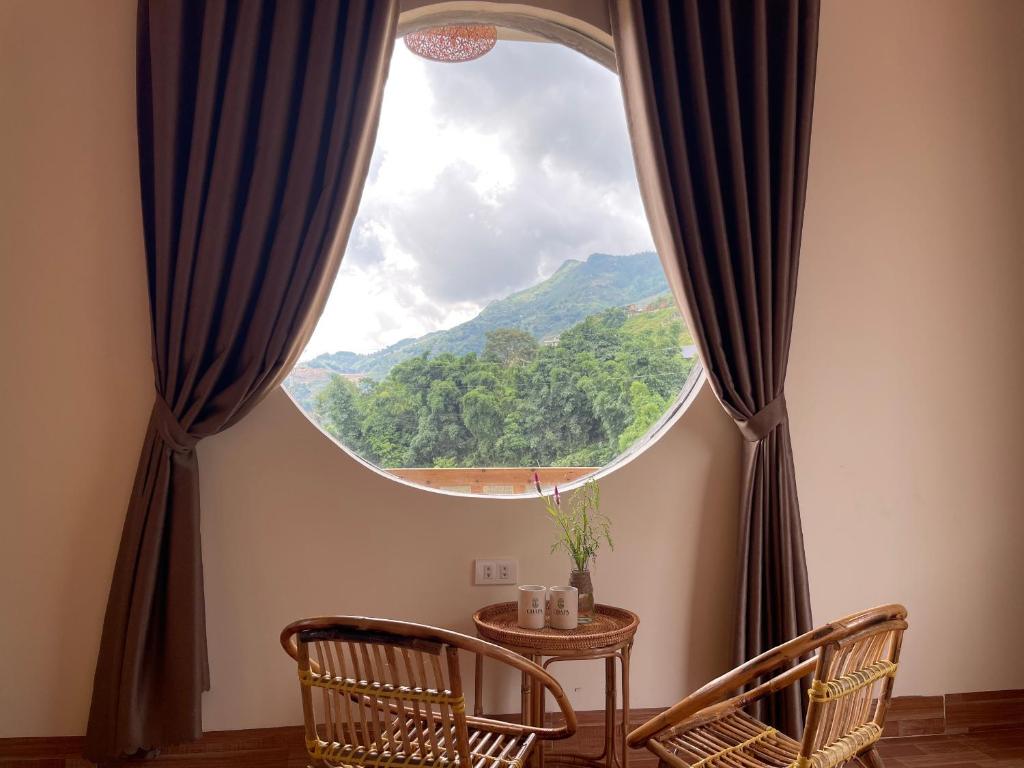 a room with a large window with a table and chairs at Nhà Bên Suối homestay in Sa Pa