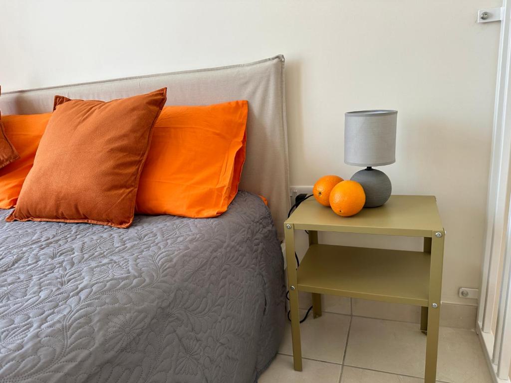 a bed with orange pillows and a table with a lamp at DoMiSol duplex suites near sea in St. Paul's Bay