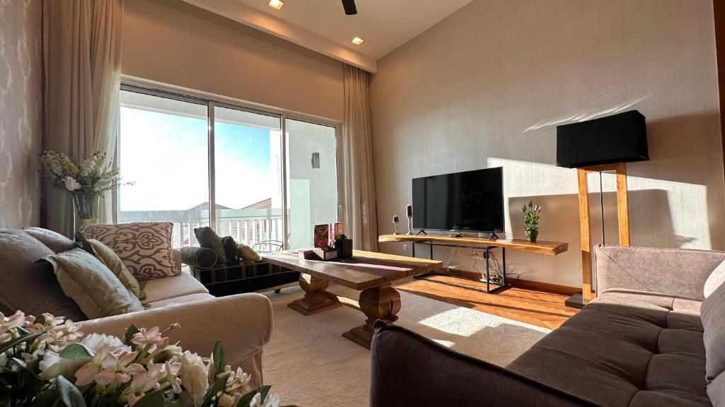 a living room with a couch and a tv at Cozy Straits Quay Seafront Suite in Tanjong Tokong