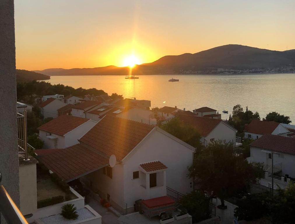 a view of a sunset over the water with houses at AC apartment in Okrug Gornji