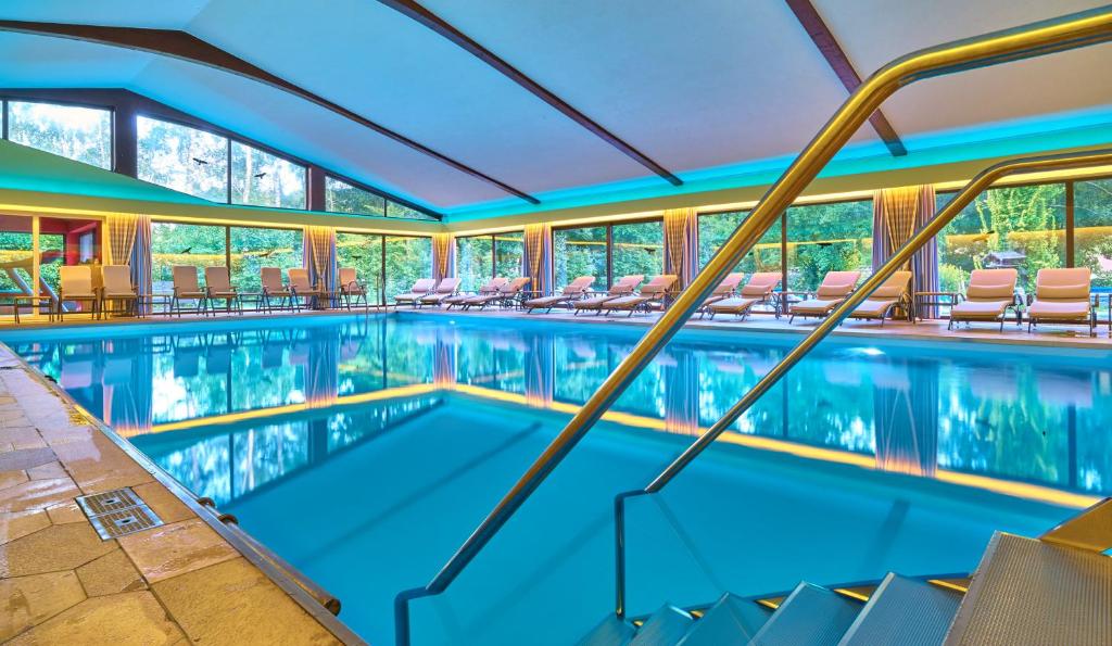 ein Schwimmbad in einem Hotel mit Stühlen und Tischen in der Unterkunft Hotel Das Bayerwald in Lam