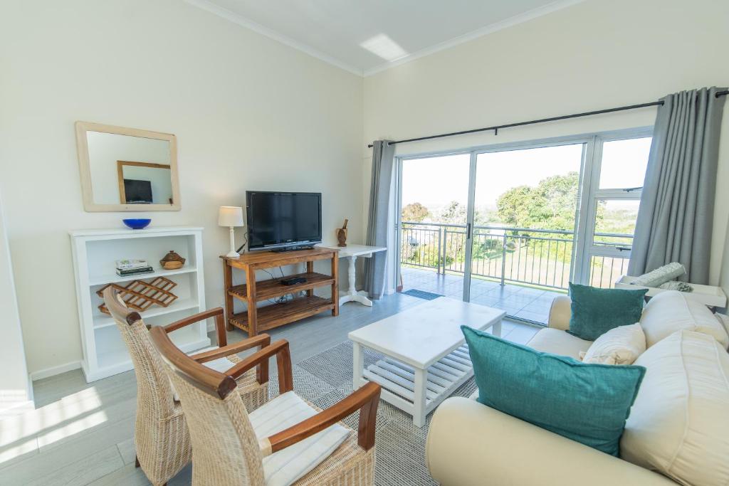 sala de estar con sofá, sillas y TV en P7 - Goose Valley - Ocean Views, en Plettenberg Bay