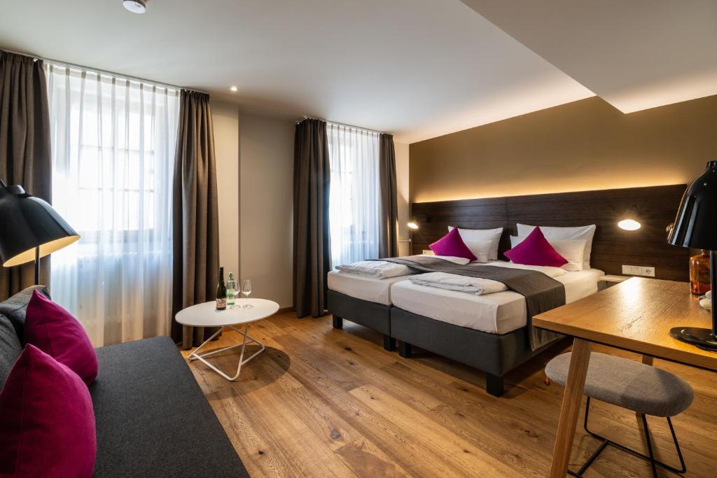 ハンメルブルクにあるMüller! Das Weingut & Weinhotelのベッド2台とソファが備わるホテルルームです。