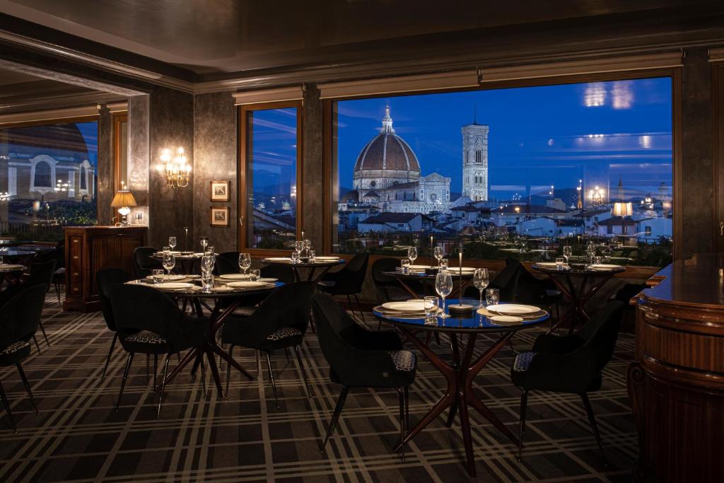 a restaurant with tables and chairs and a view of the city at Grand Hotel Baglioni in Florence