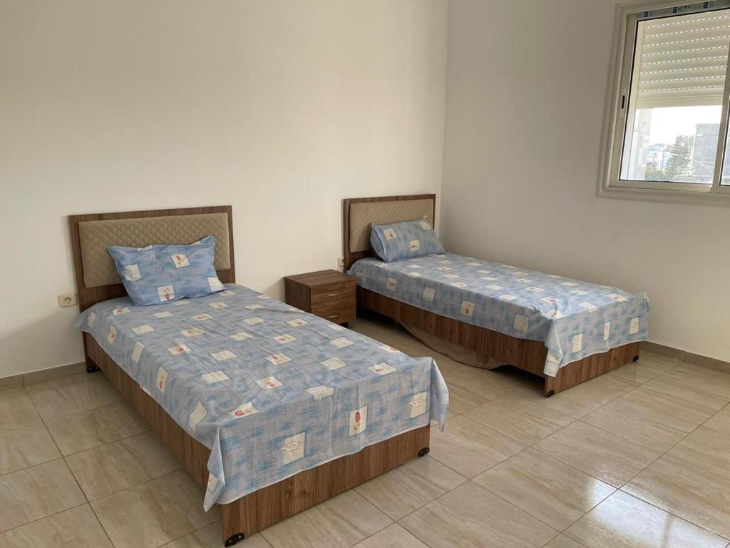 a room with two beds and a window at Spatious ground floor appartement near to the beach in Sousse