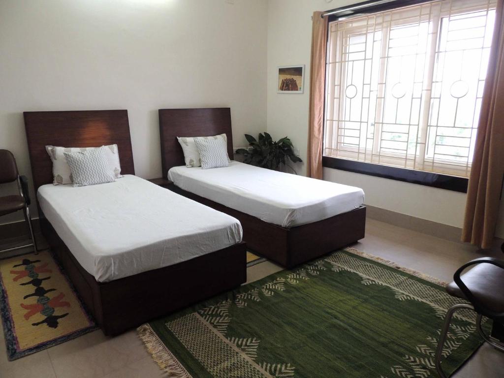 1 Schlafzimmer mit 2 Betten, einem Fenster und einem Teppich in der Unterkunft Sublime Homestay in Bhubaneshwar