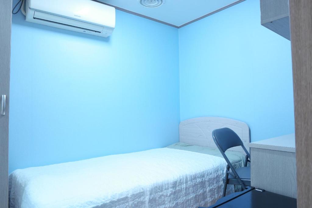Cette chambre dispose d'un lit et d'une chaise avec des lumières bleues. dans l'établissement Anire, à Busan
