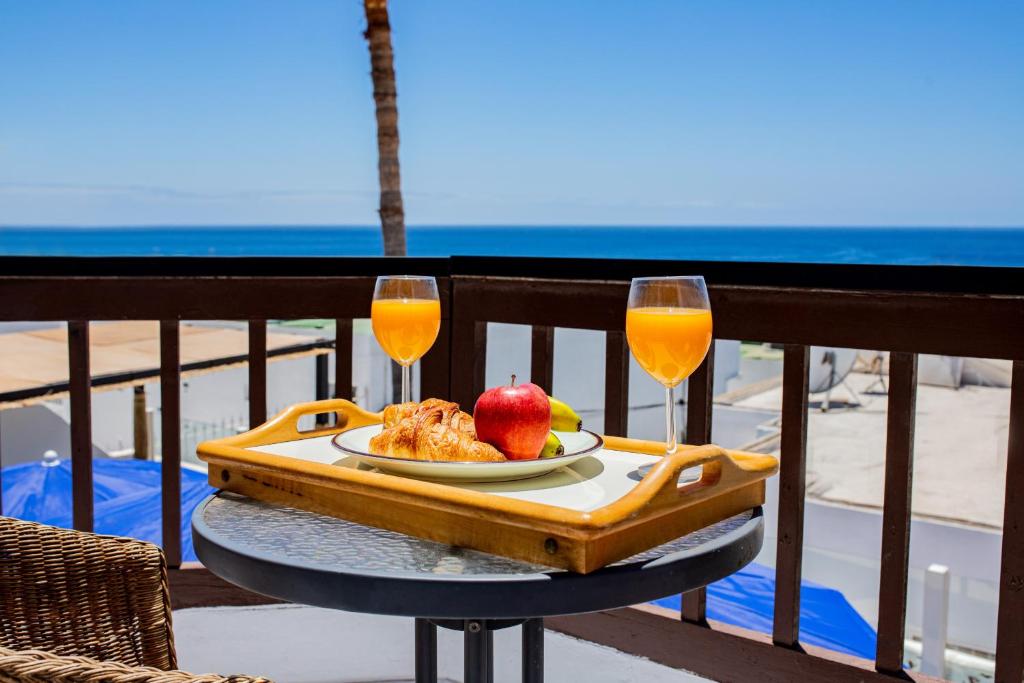 a table with a plate of food and two glasses of orange juice at Penthouse Ocean View Puerto del Carmen in Puerto del Carmen
