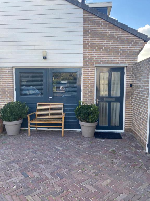 a wooden bench sitting in front of a house at sunshine in Schoorl