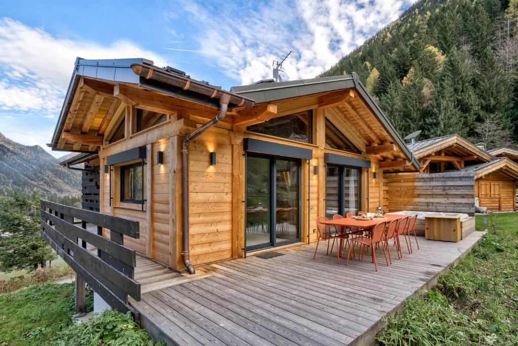 a wooden cabin with a table on a deck at Chalet Green Forest in Chamonix