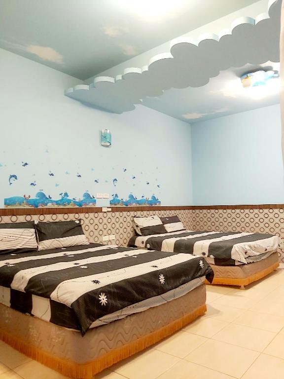 two beds in a room with birds on the wall at Happy Heart B&amp;B in Taitung City