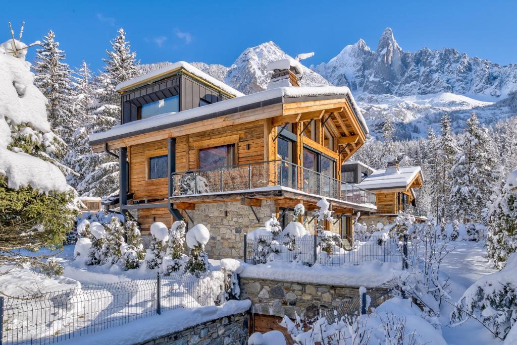 a log cabin in the snow with mountains in the background at Chalet Red Fox in Chamonix-Mont-Blanc