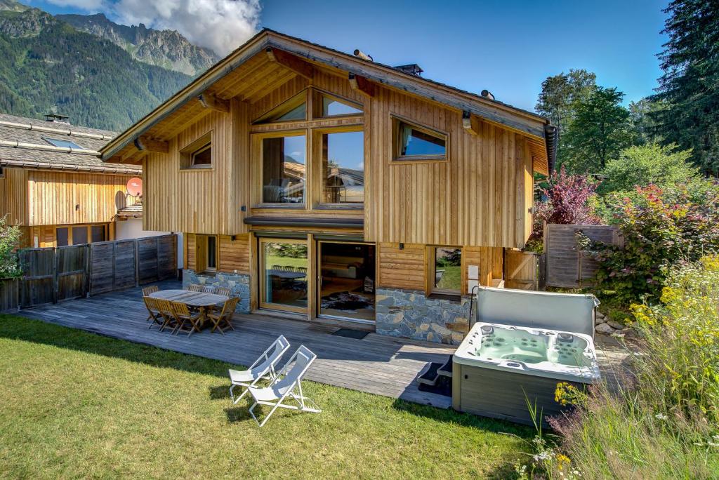 een houten huis met een terras en stoelen in de tuin bij Chalet Planards 2 in Chamonix-Mont-Blanc