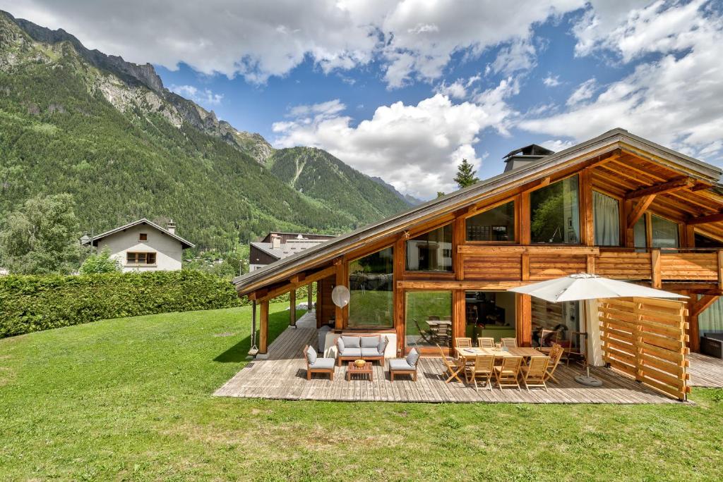 een huis met een groot terras met stoelen en een parasol bij Chalet Caleris in Chamonix-Mont-Blanc