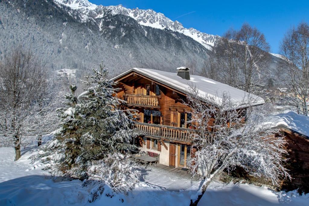 una cabaña de madera en la nieve con un árbol de Navidad en Chalet les Sauberands, en Chamonix-Mont-Blanc