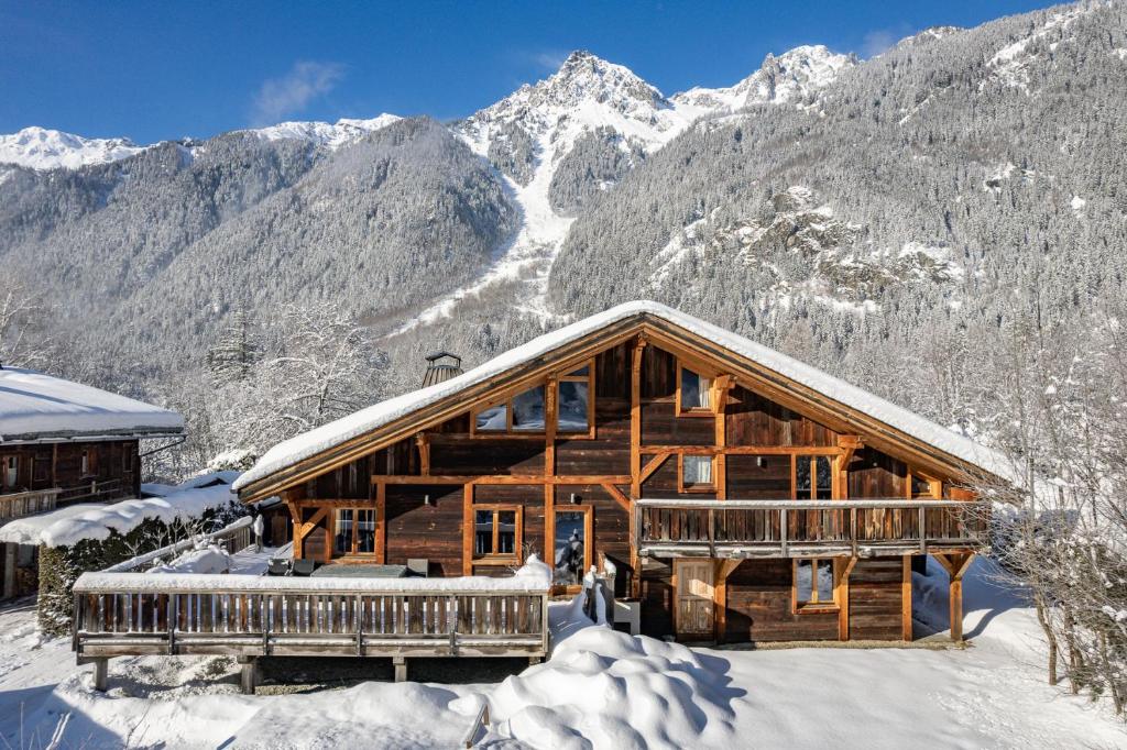 une cabane en rondins dans la neige avec des montagnes en arrière-plan dans l'établissement Chalet Amelie, à Chamonix-Mont-Blanc