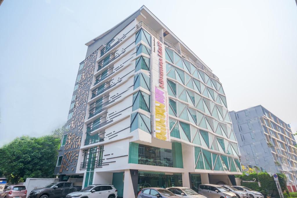 ein hohes Gebäude mit davor geparkt in der Unterkunft Nimman Mai Design Hotel Chiang Mai - SHA Plus in Chiang Mai