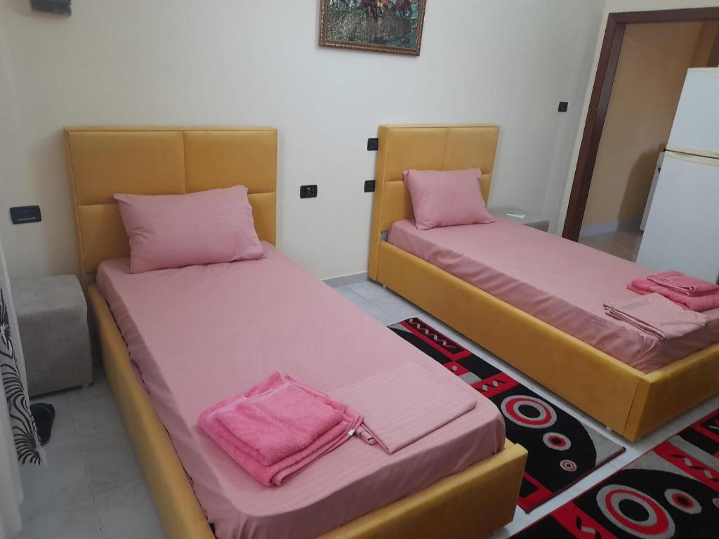 twee bedden in een kamer met roze lakens bij Veri's house in Tirana